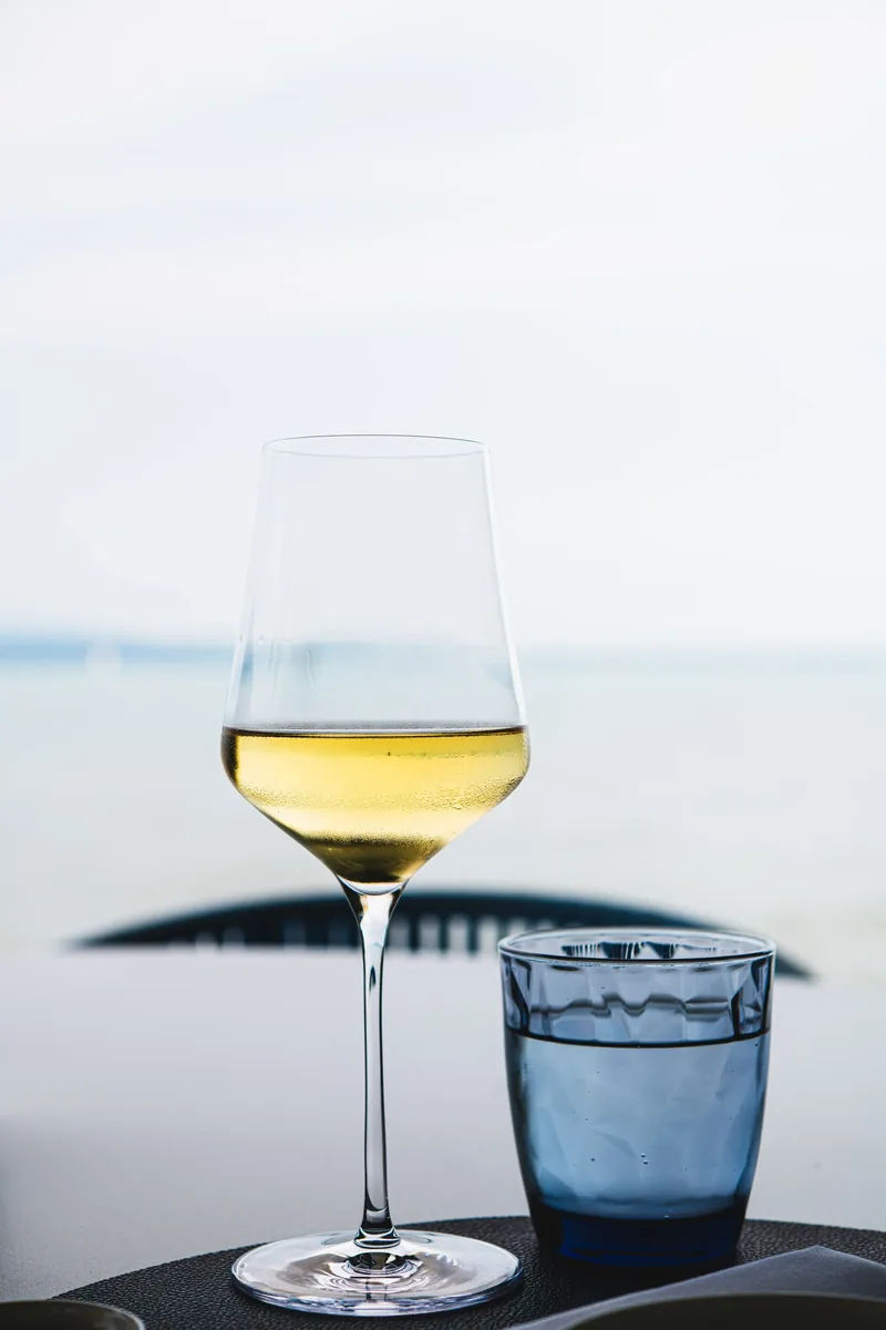 Ein Glas Weisswein und ein Wasserglas vor dem See