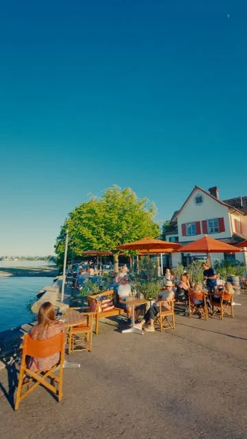 Gäste auf den Stühlen an der Promenade, dahinter die Wirtschaft
