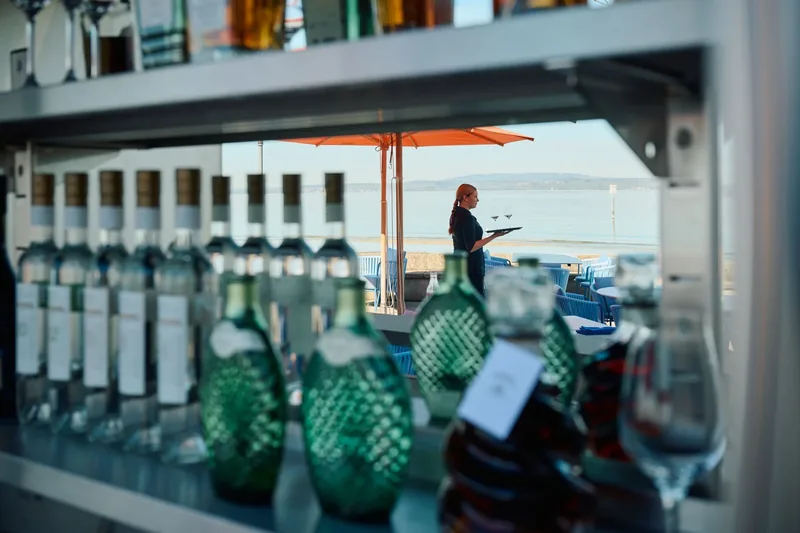 Flaschen im Regal an der Bar, durch die Scheibe der See