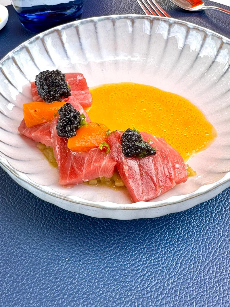 Thunfisch mit Kaviar und Sauce in der gerippten Schale auf dem blauen Platzteller